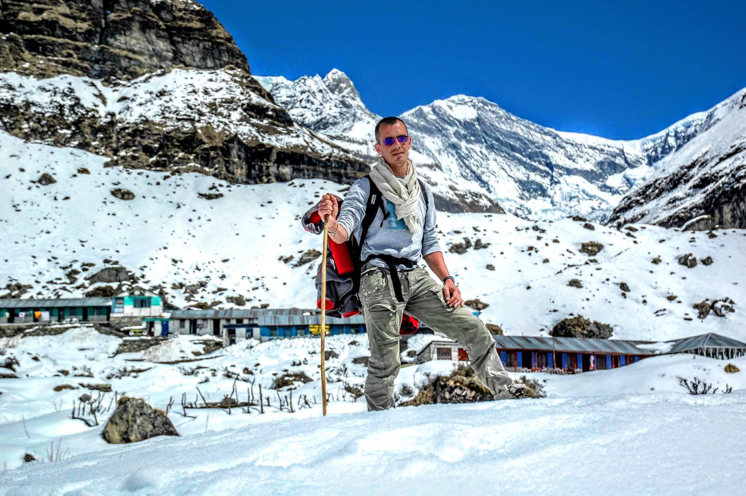 Image Annapurna Mountain with a man standing in between the image,stading with the help of stick in his hand. - Annapurna Base Camp Trek | Hiking Himalayas Treks & Expedition
